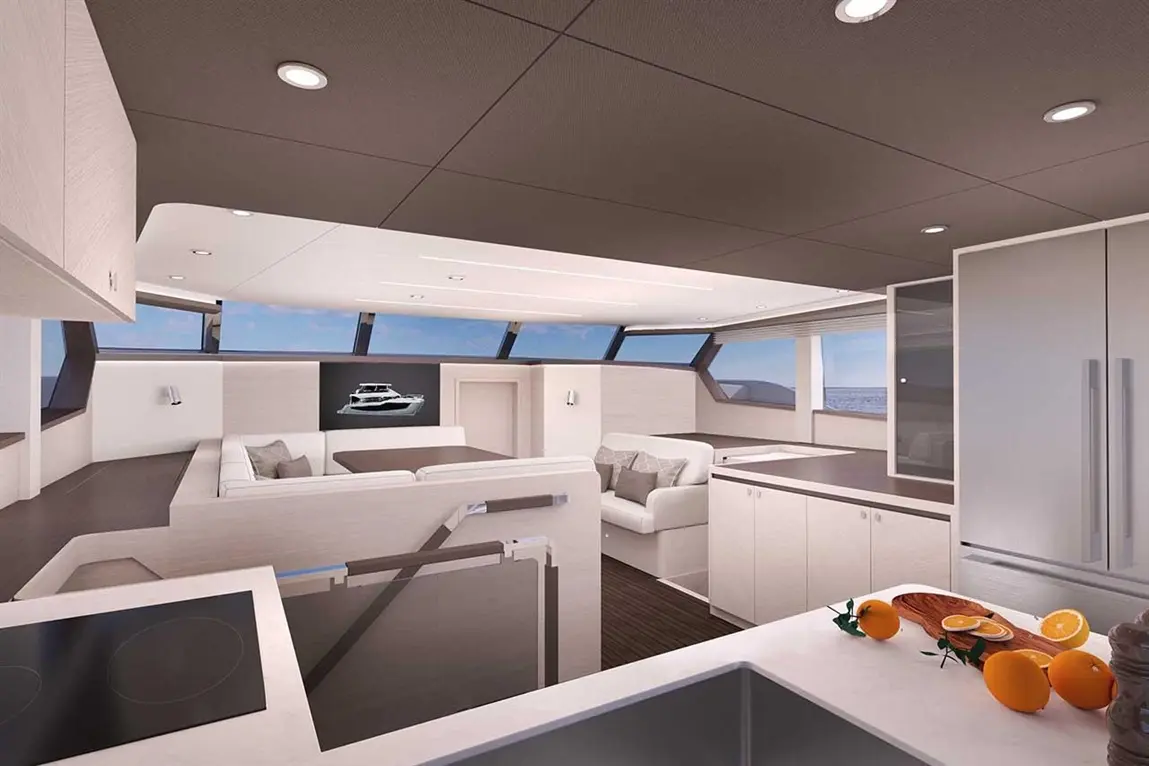 Modern yacht interior showcasing a spacious lounge with a sofa, dining area, and a kitchen with oranges on the counter.